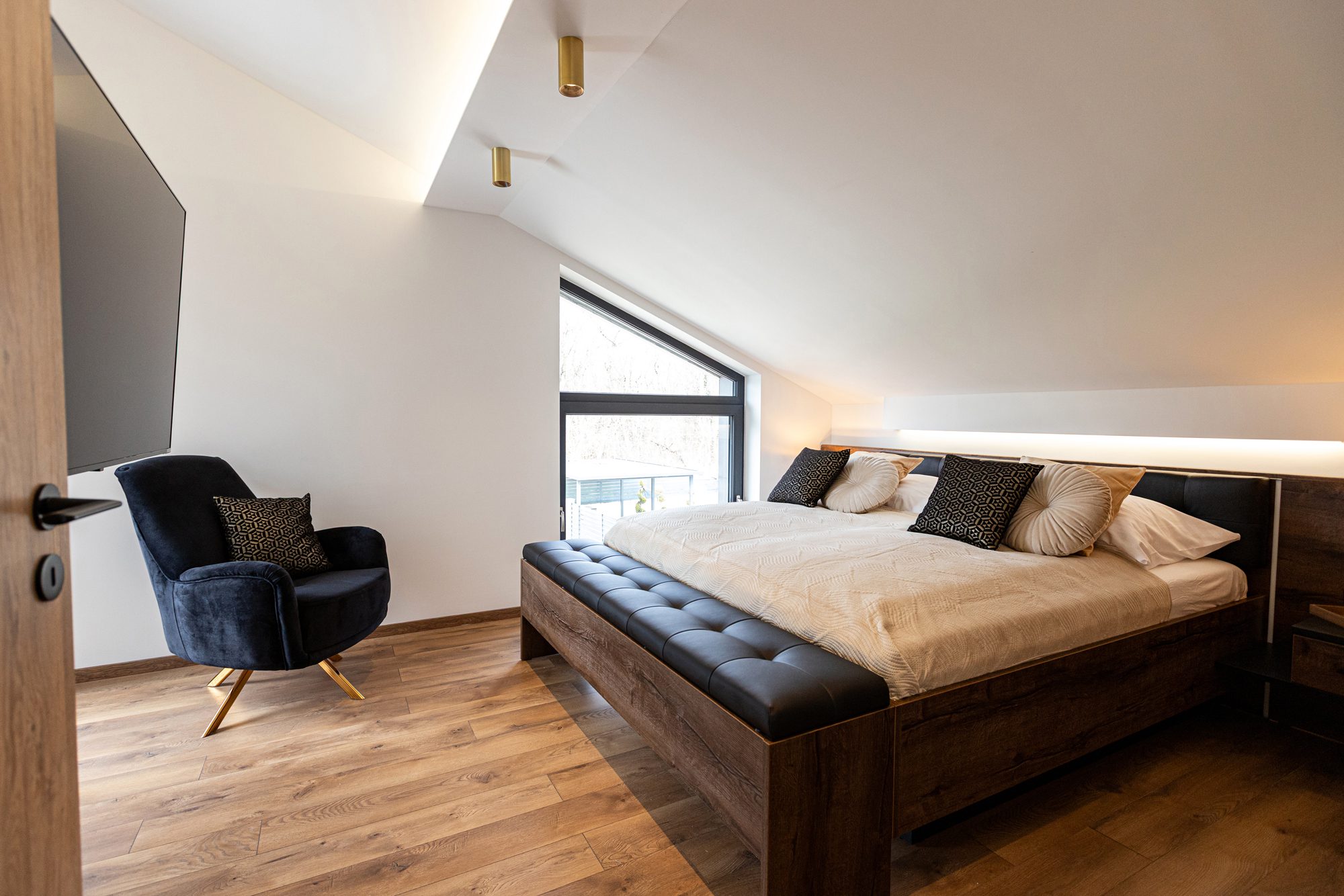 Living space villa Lake Balaton - Villa Porta Verde I bedroom with TV and dark blue velvet armchair