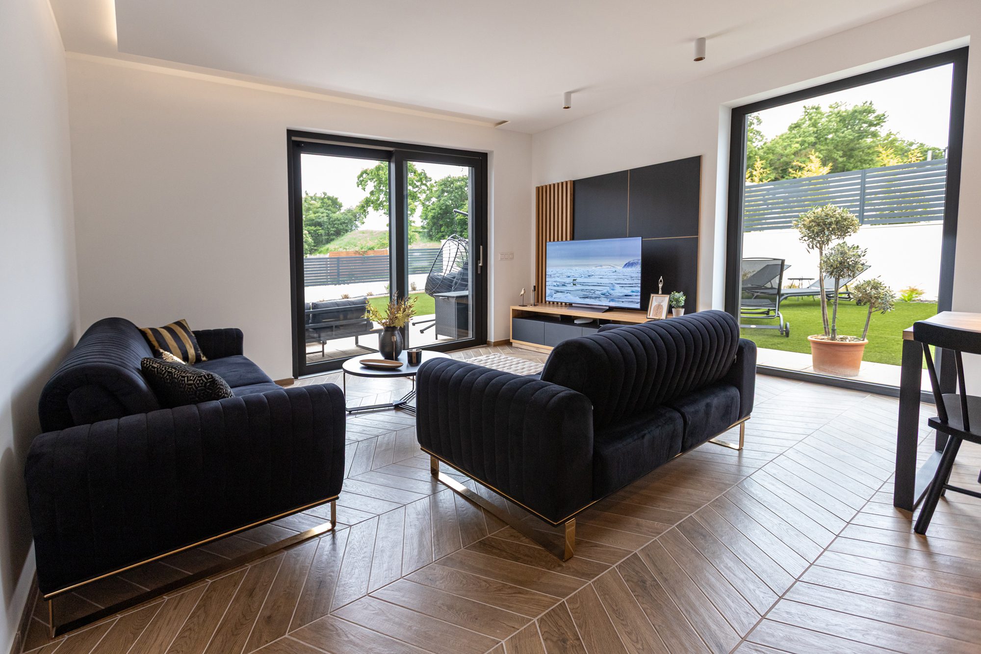 Living space villa rental Hungary - Villa Porta Verde II living room with black velvet sofas and backyard view
