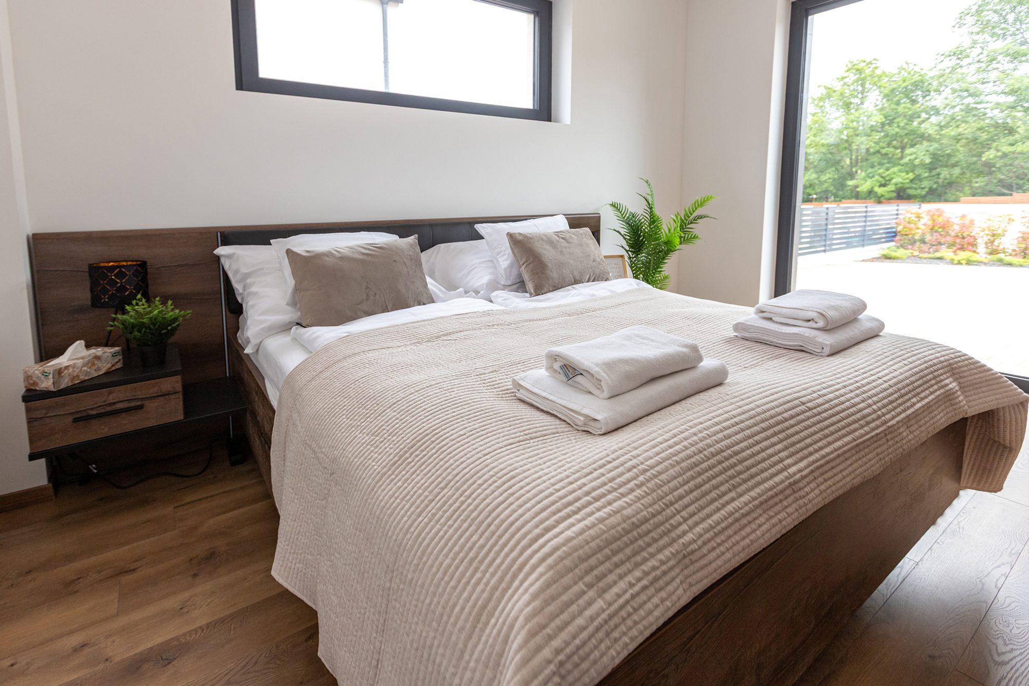 Bedroom villa accommodation Balatonalmádi - Villa Porta Verde II bedroom with wooden headboard and glass door